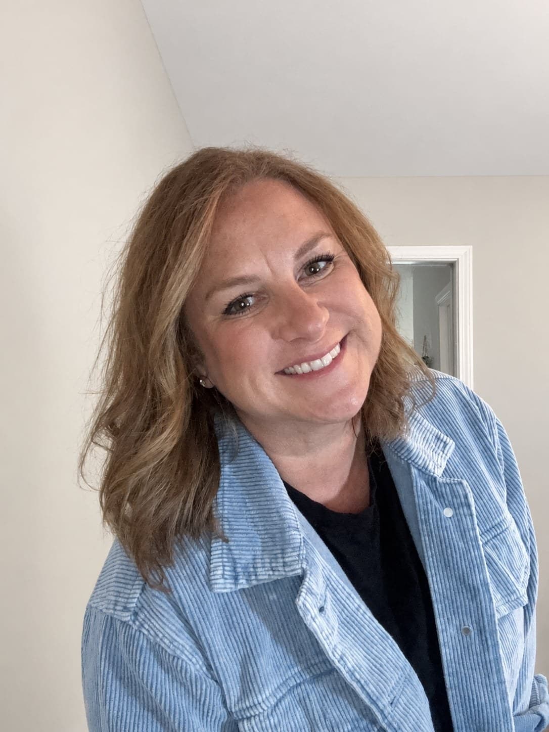Erin smiling in a blue corduroy jacket